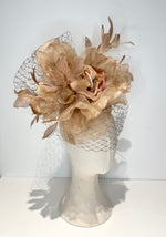 Beige floral headpiece with a veil on a mannequin head against a white background